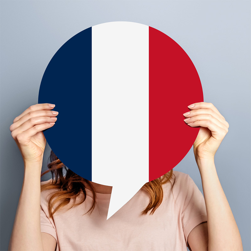 프랑스 국기 말풍선을 얼굴 앞에 든 성인 — 프랑스어 수업 안내 페이지 히어로 이미지